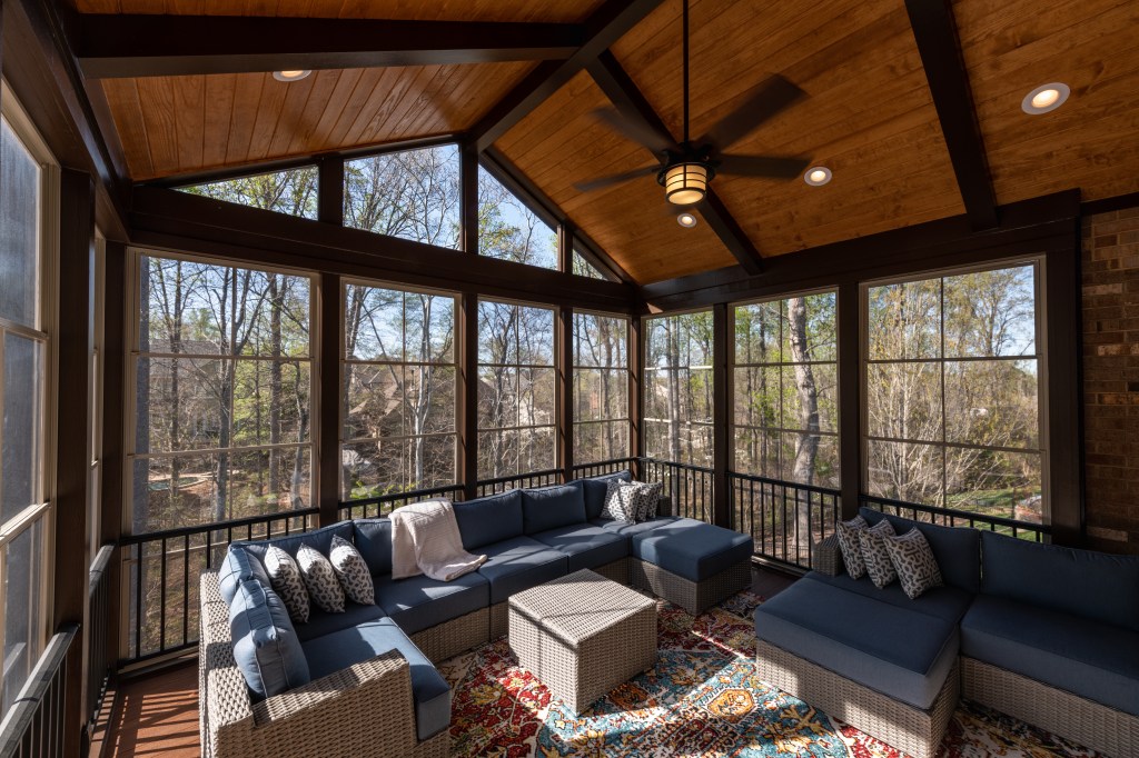 Cozy screened porch in springtime, full of blooms trees in the background.